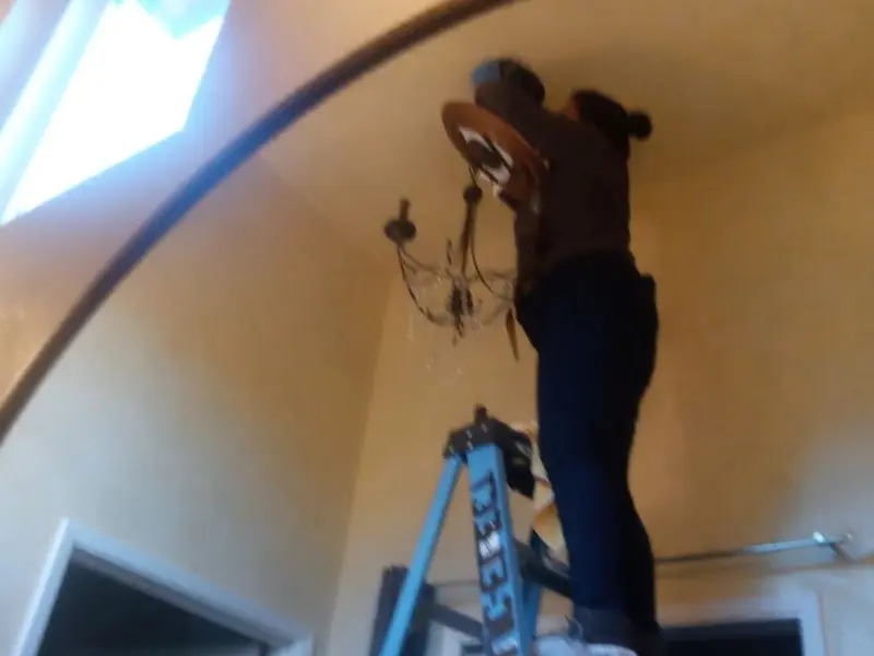 Electrician installing a chandelier in a Dallas residence